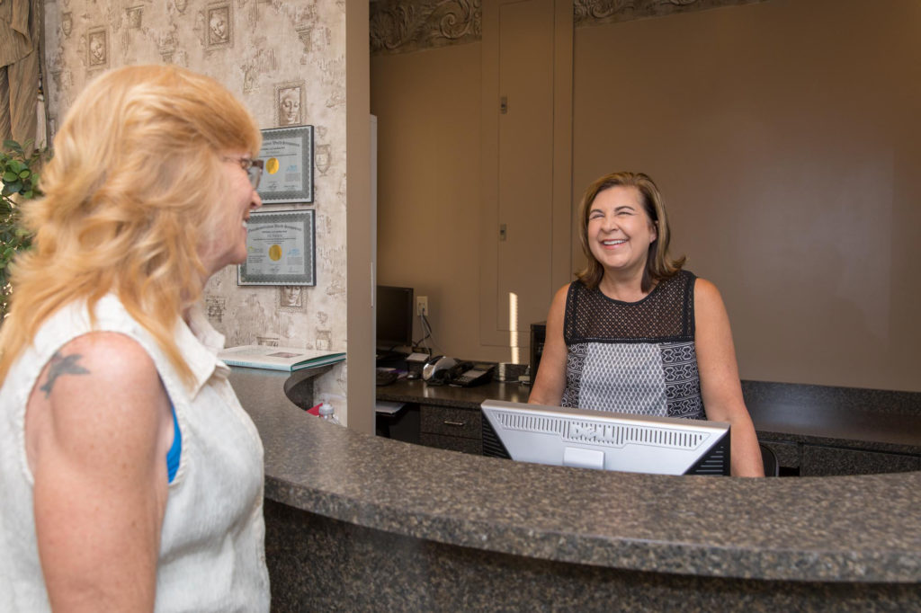 female receptionist greeting a patient at the facial surgery center